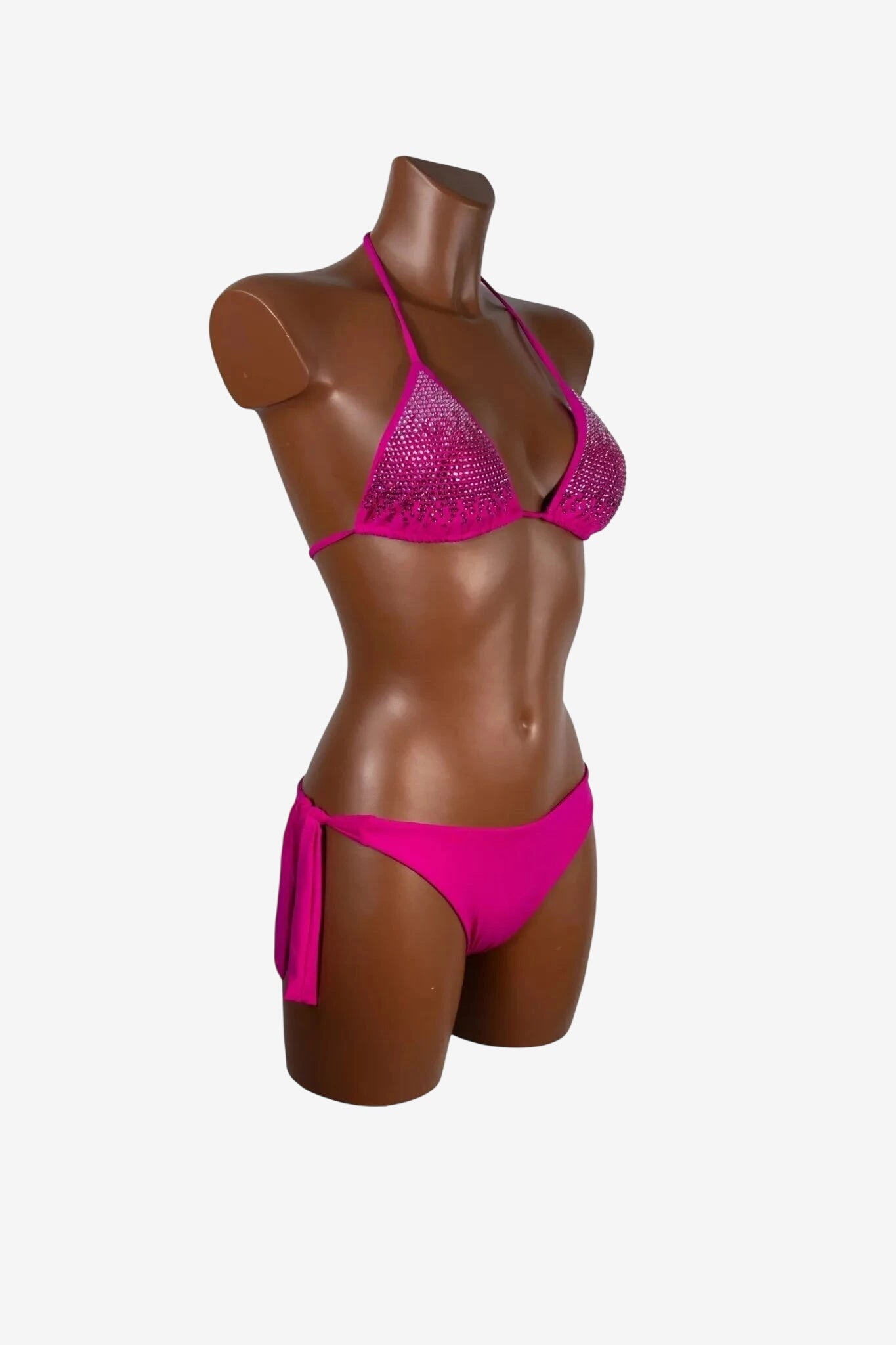 Bikini a triangolo fucsia con decorazioni di strass su un manichino.