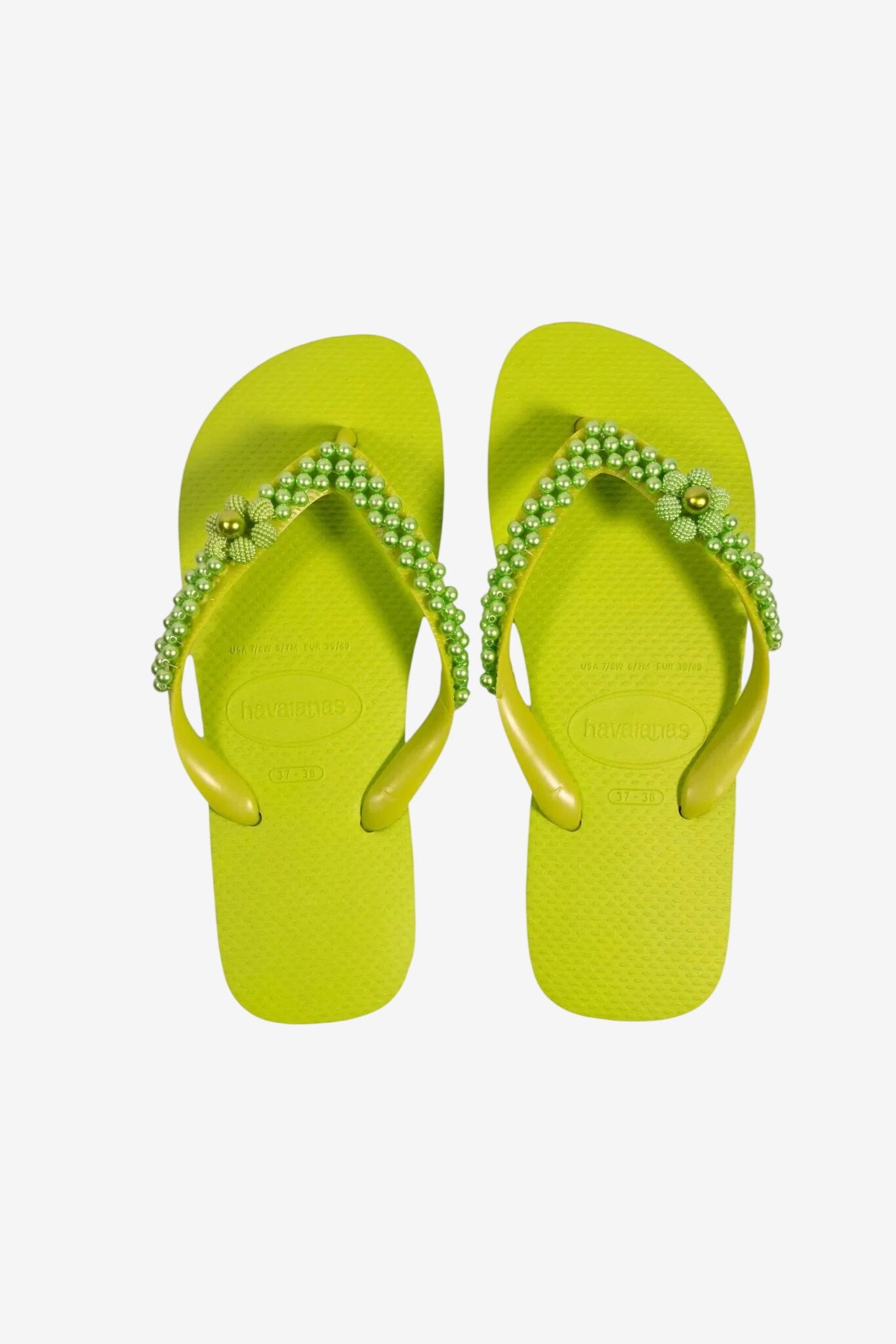 Infradito da donna color lime fluo decorate con perline verdi e un fiore centrale sul cinturino.