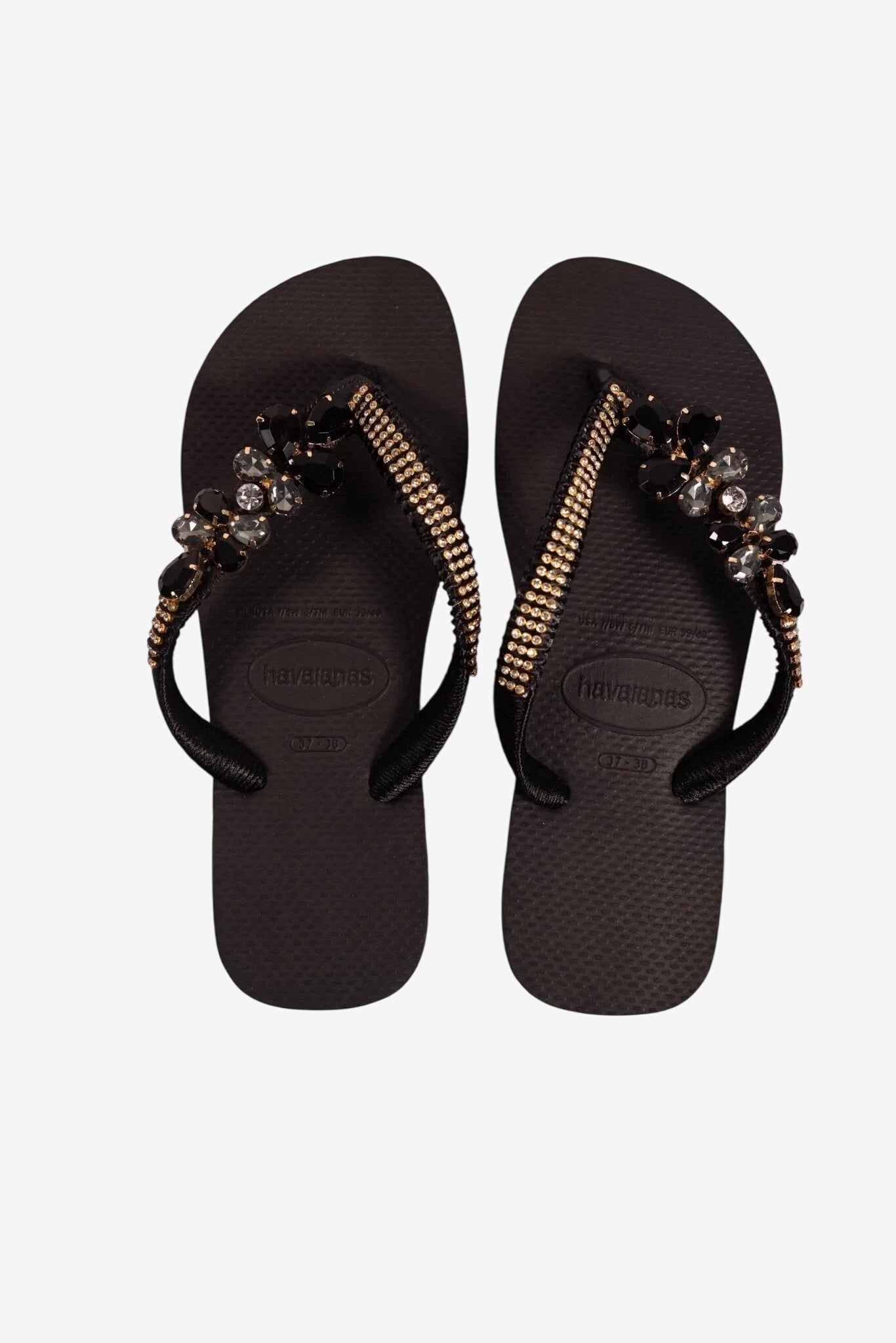 Infradito nere da donna con cinturini decorati da strass e pietre scure.