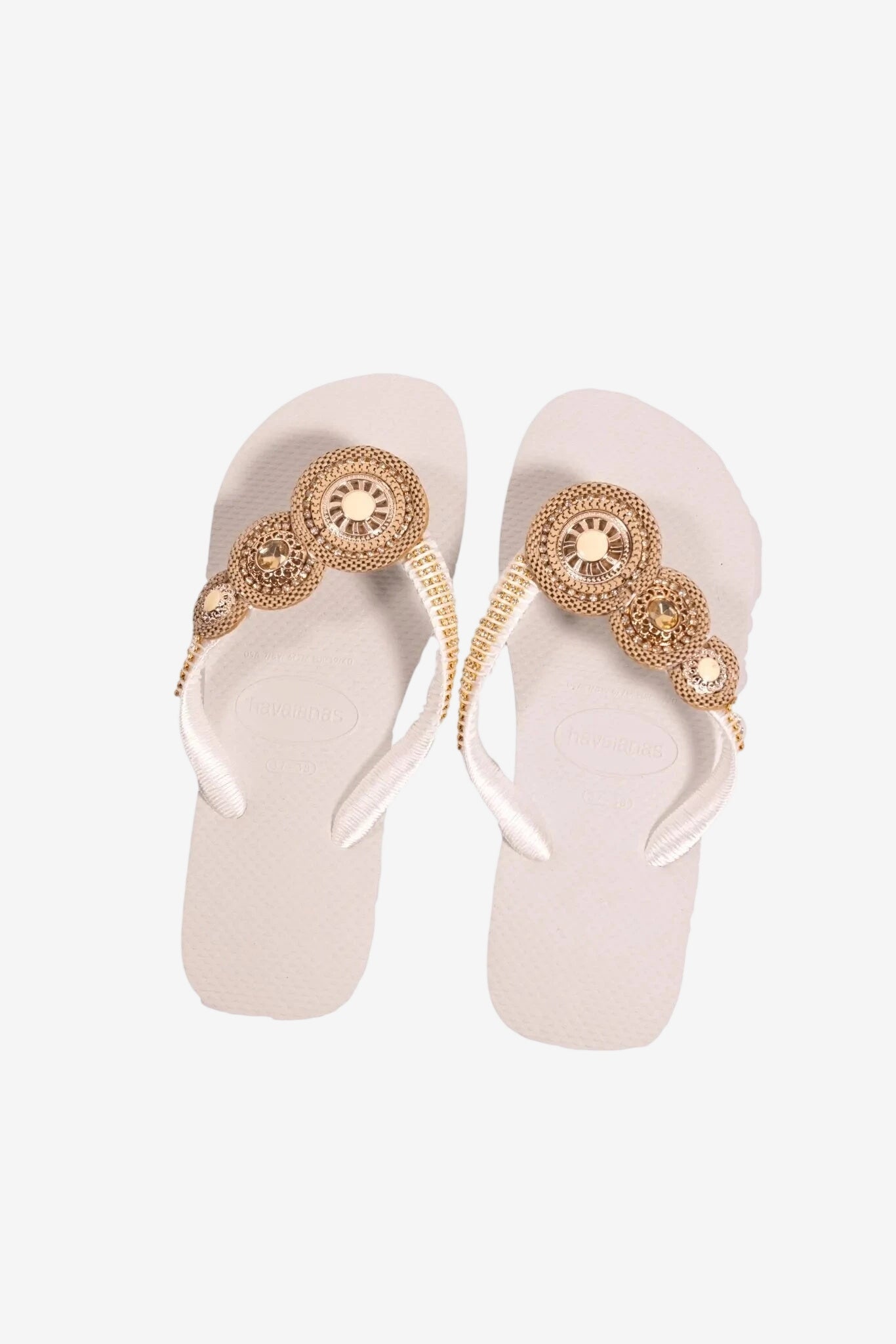 Infradito bianche da donna con cinturini decorati da elementi circolari color oro.