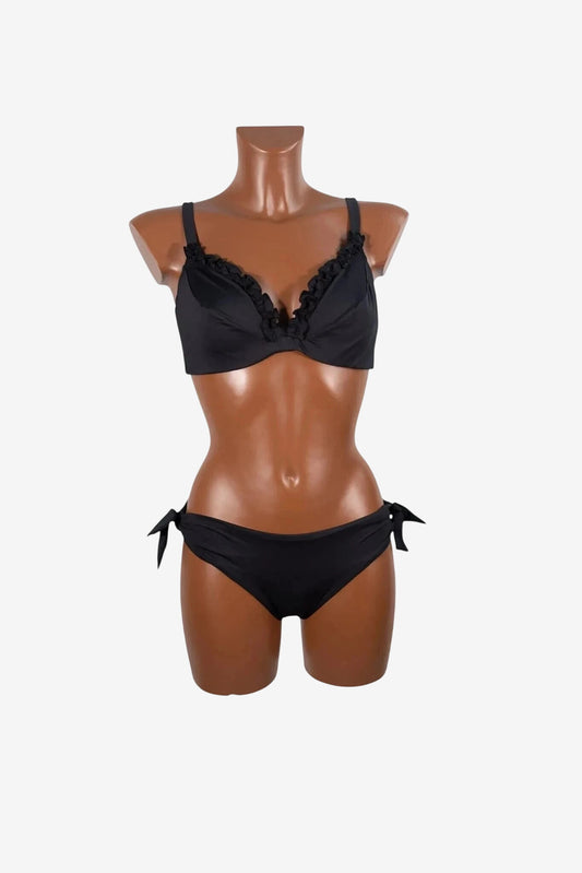 A black bikini set with a ruffled trim on the underwire top and tie-side bottoms on a mannequin.