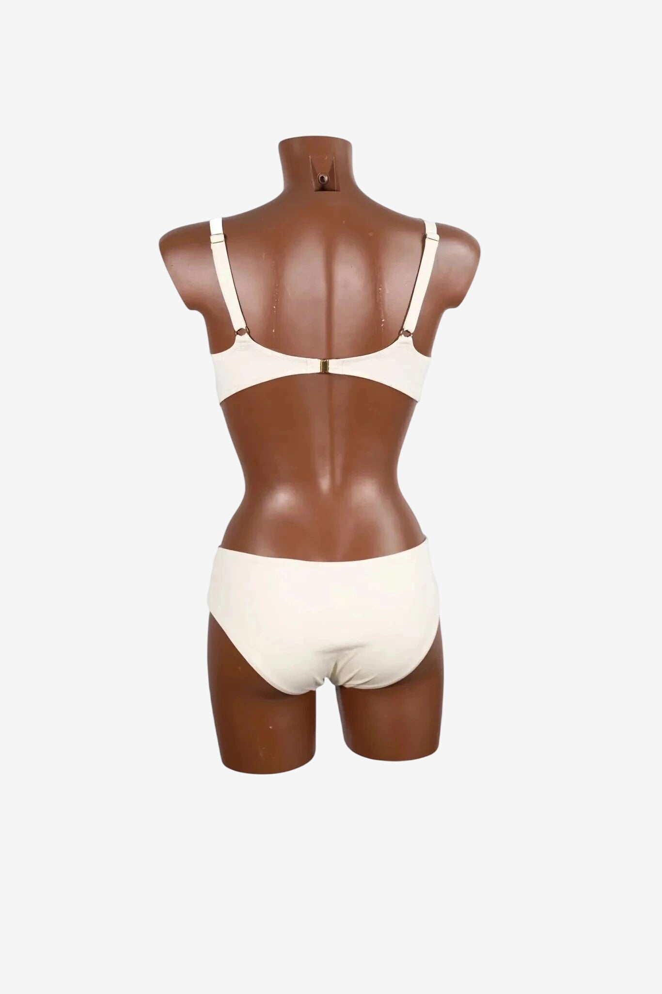 A white bralette and matching bikini bottom set displayed on a brown mannequin from the back.