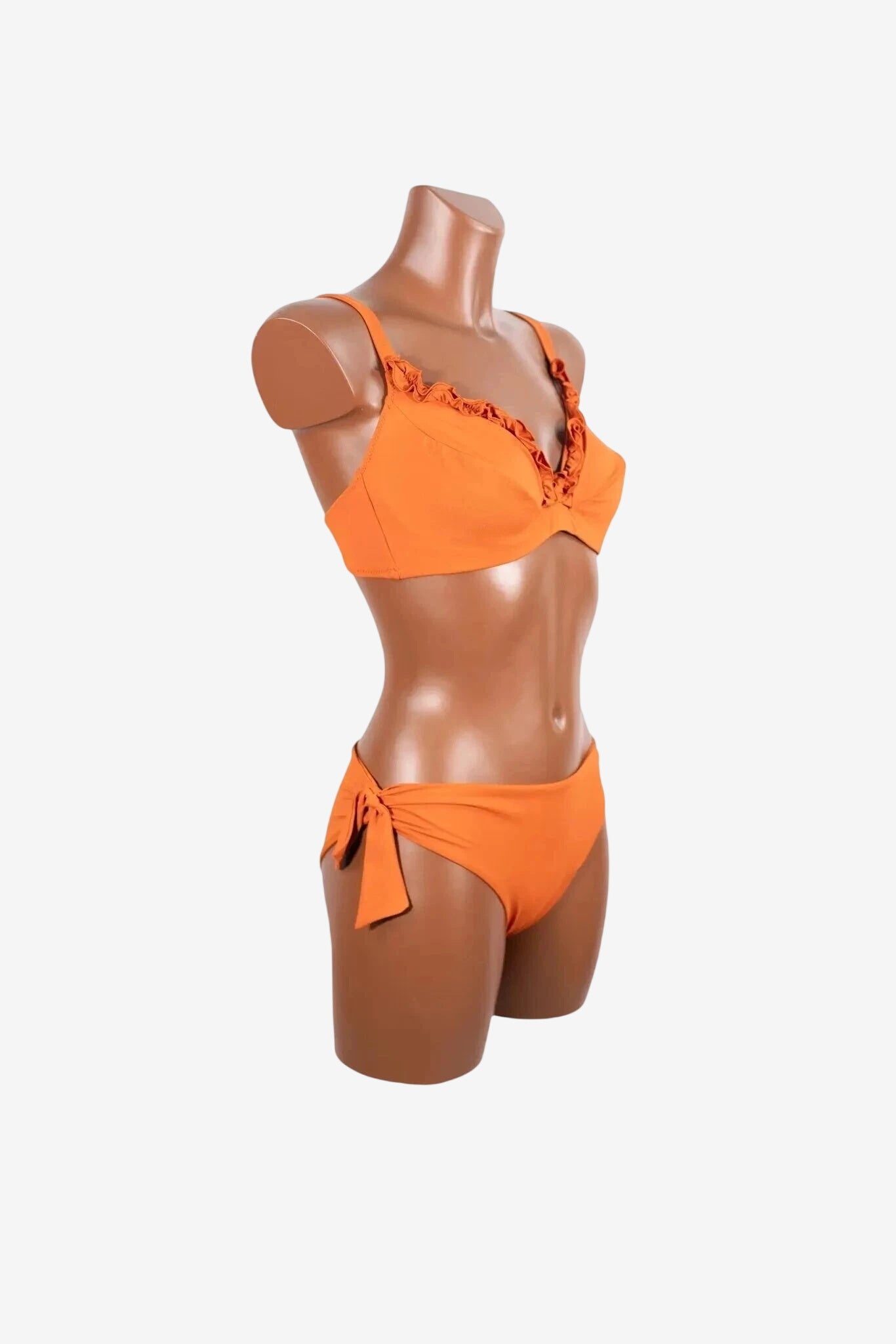 A bright orange bikini set with ruffled trim on the cups and a side-tie bottom on a mannequin.