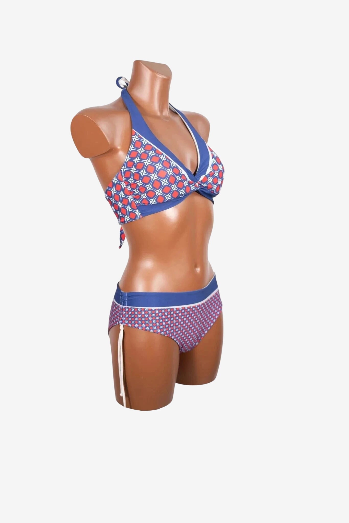Bikini triangolare con motivo geometrico rosso e blu su un manichino.