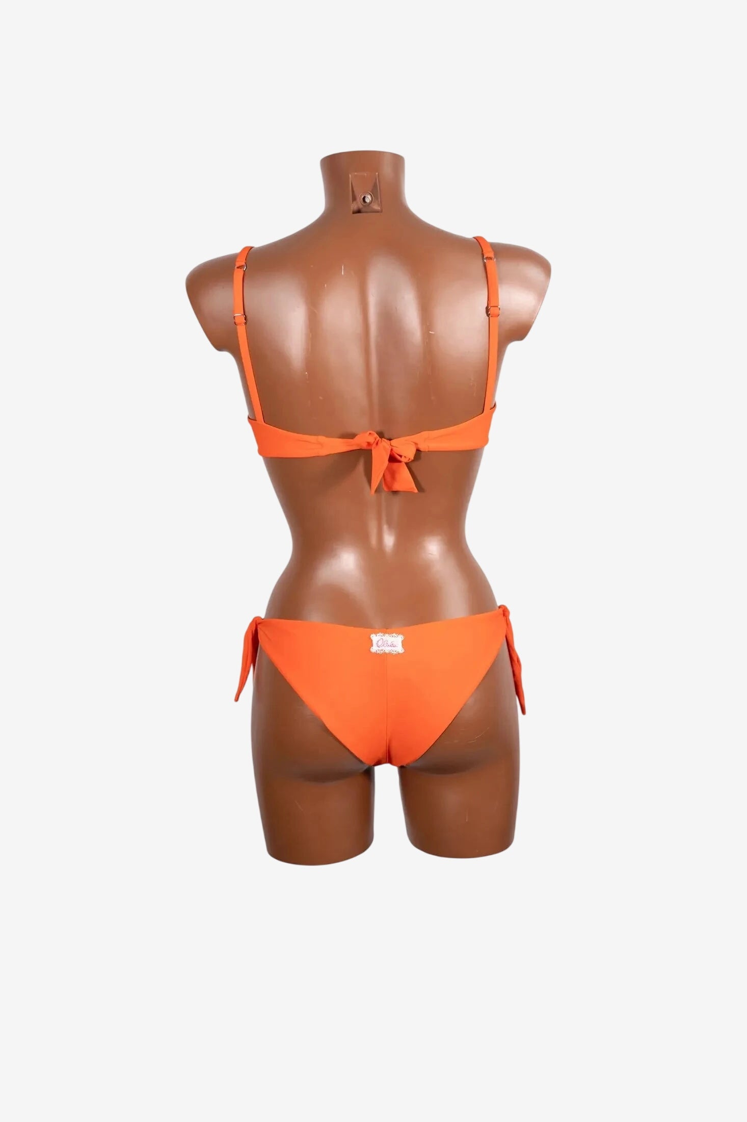 Bikini bralette arancione senza ferretto con chiusura a fiocco sul retro su manichino.