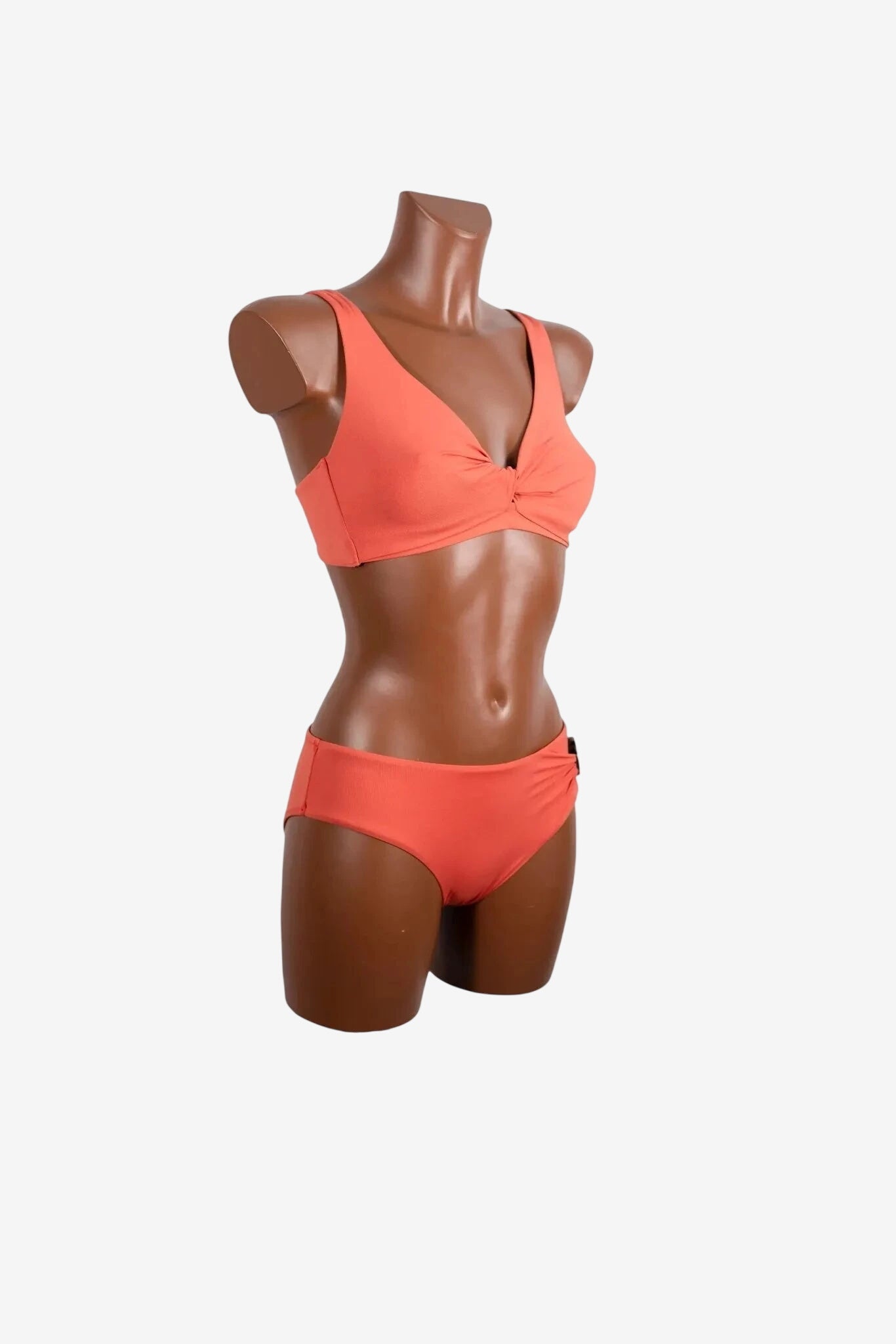 Bikini color corallo con reggiseno a triangolo e slip a vita bassa su manichino.