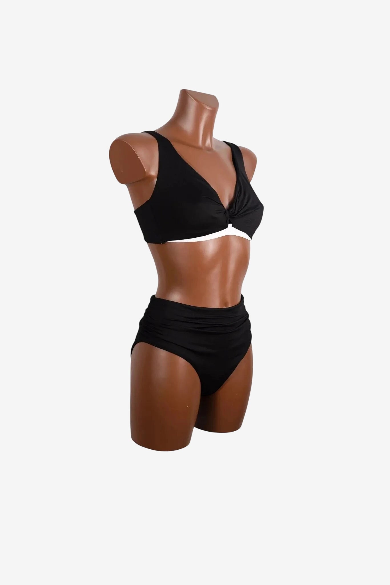 Bikini nero a due pezzi con top a V annodato e slip a vita alta arricciato su manichino.