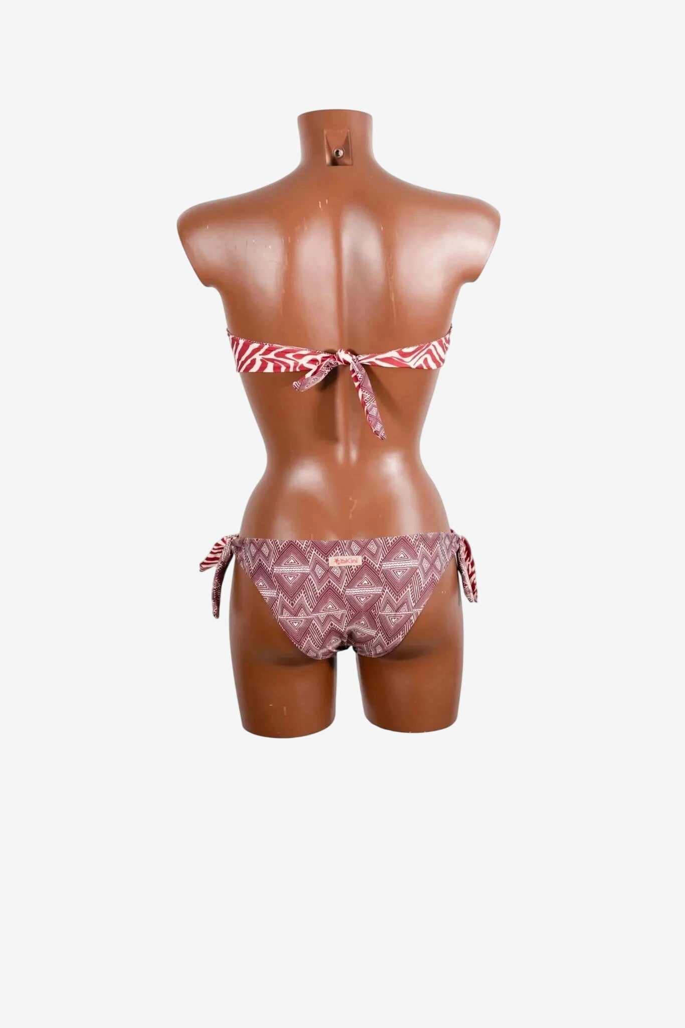 Bikini a fascia con fantasia geometrica e slip con laccetti laterali su manichino.