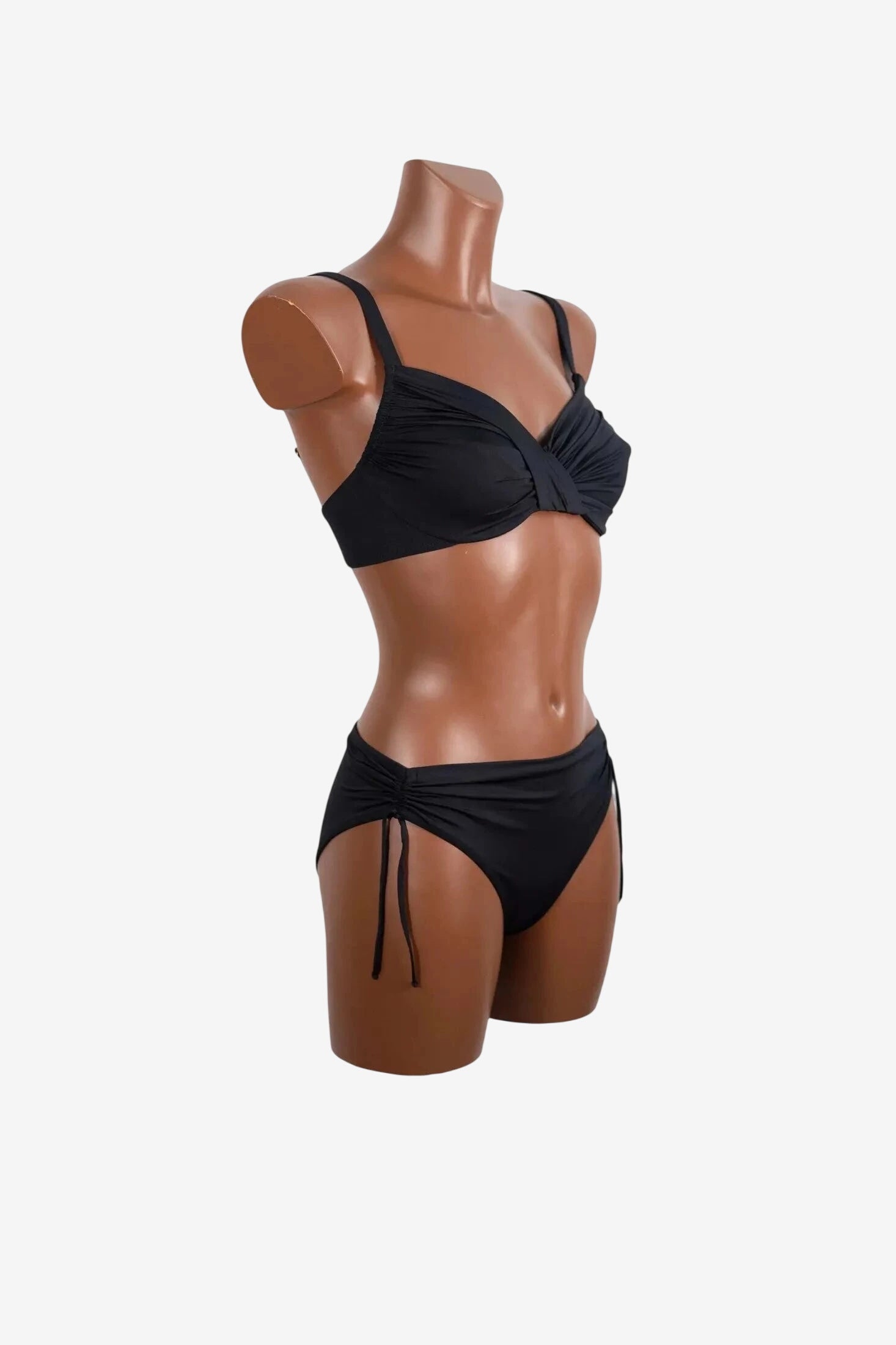 A black two-piece bikini with a ruched underwire top and matching side-tie bottoms on a mannequin.