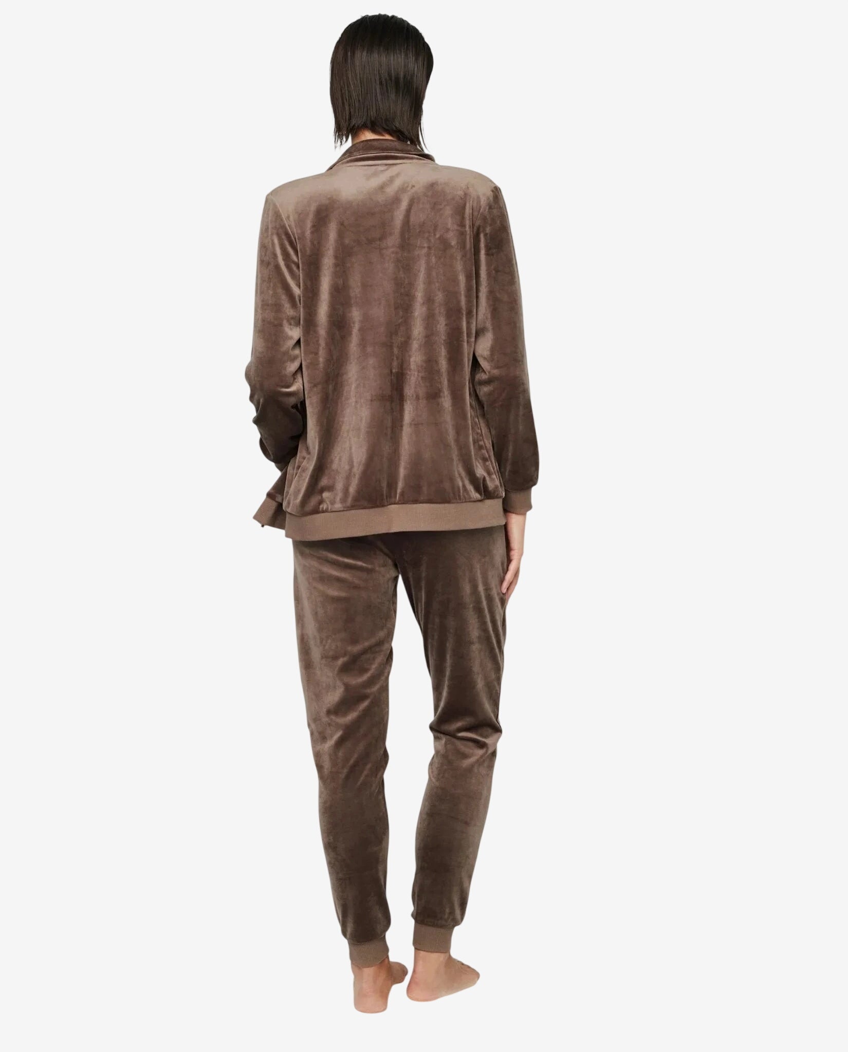 Modella di spalle indossa una tuta in ciniglia marrone con giacca a zip e pantaloni coordinati.