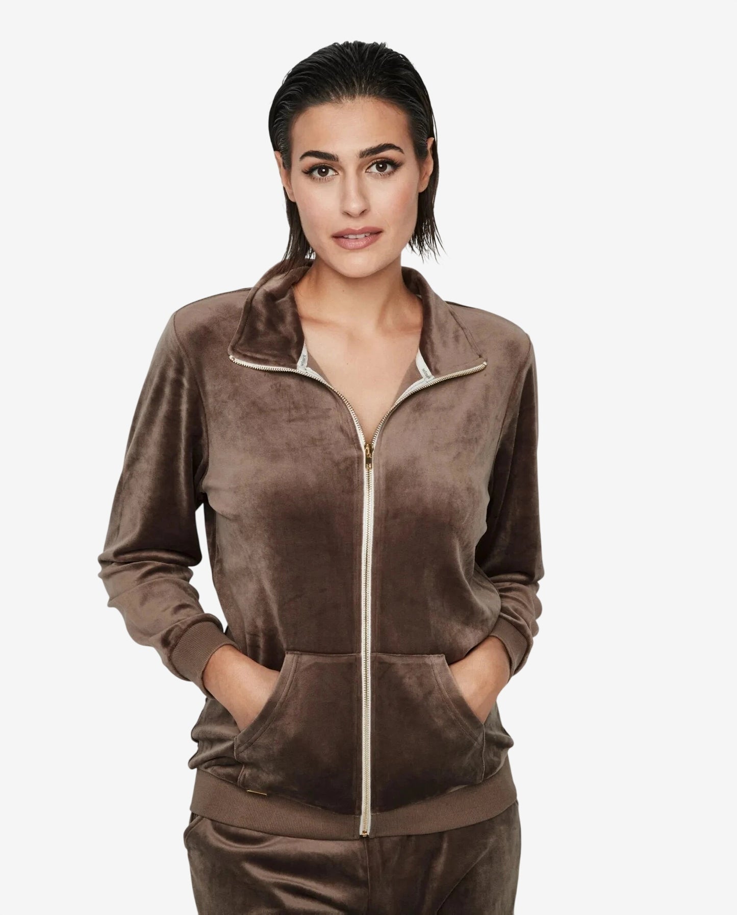 Modella indossa una giacca marrone in ciniglia con zip frontale e tasche a marsupio.