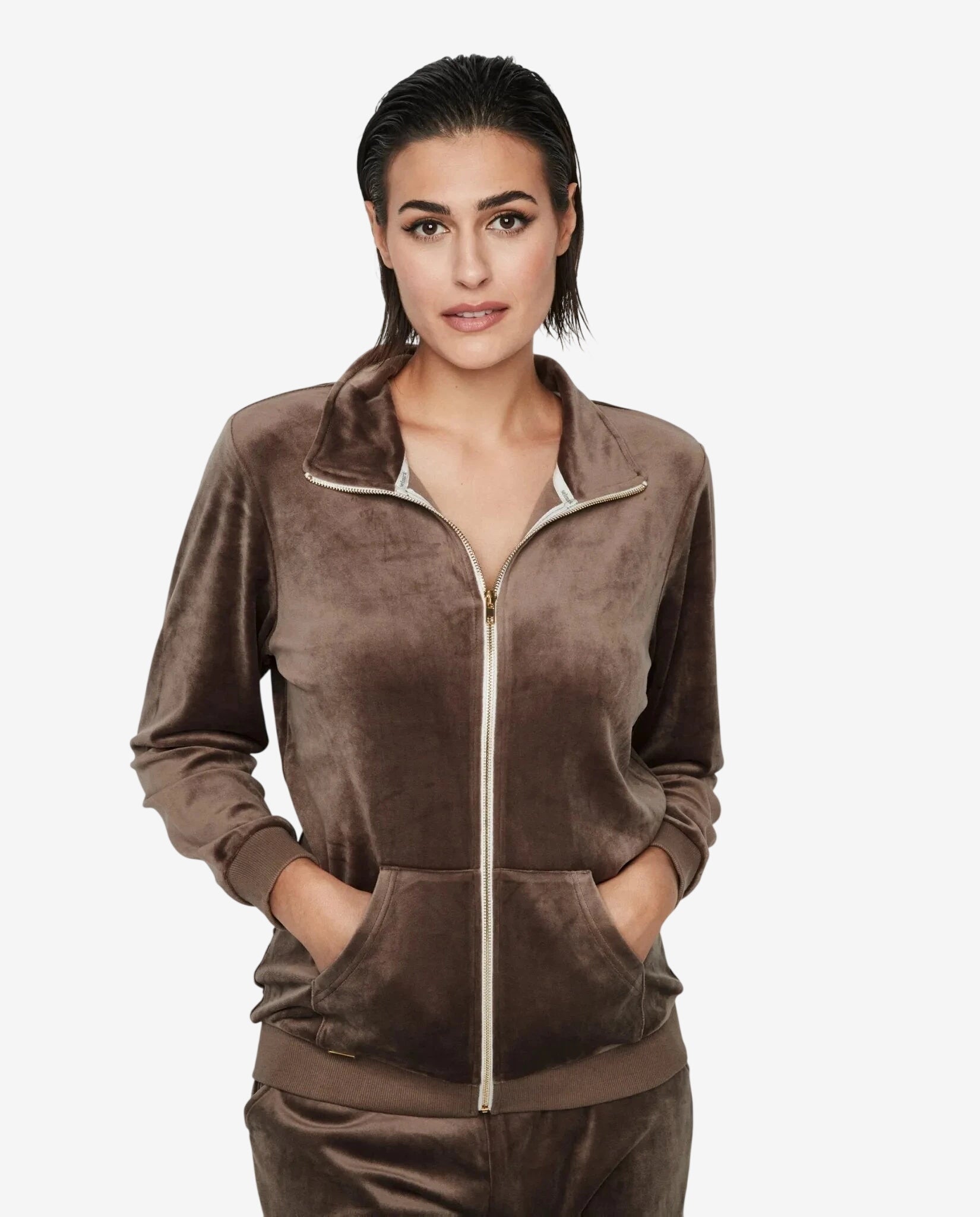 Modella indossa una giacca marrone in ciniglia con zip frontale e tasche a marsupio.