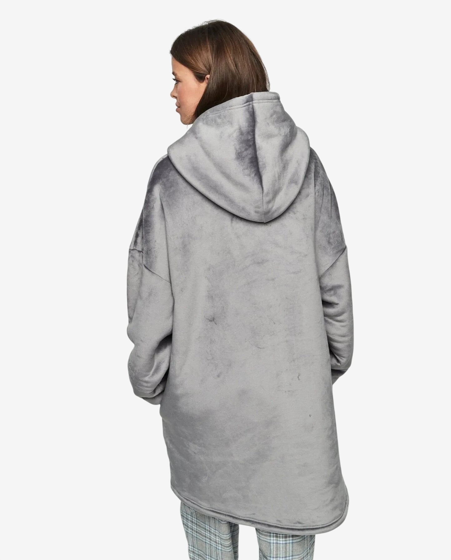 Donna di spalle che indossa un abito oversize grigio in morbido tessuto con cappuccio.