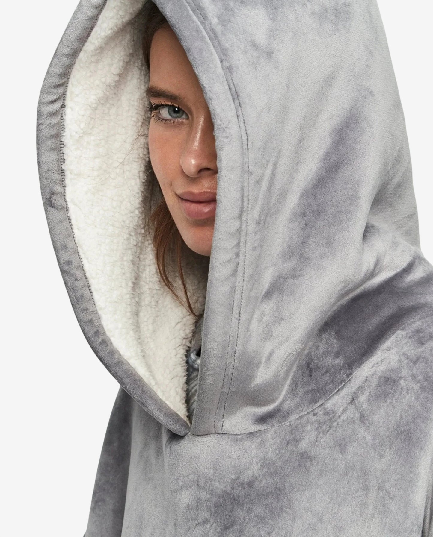 Donna che indossa un abito oversize grigio in morbido tessuto con cappuccio foderato in pile.