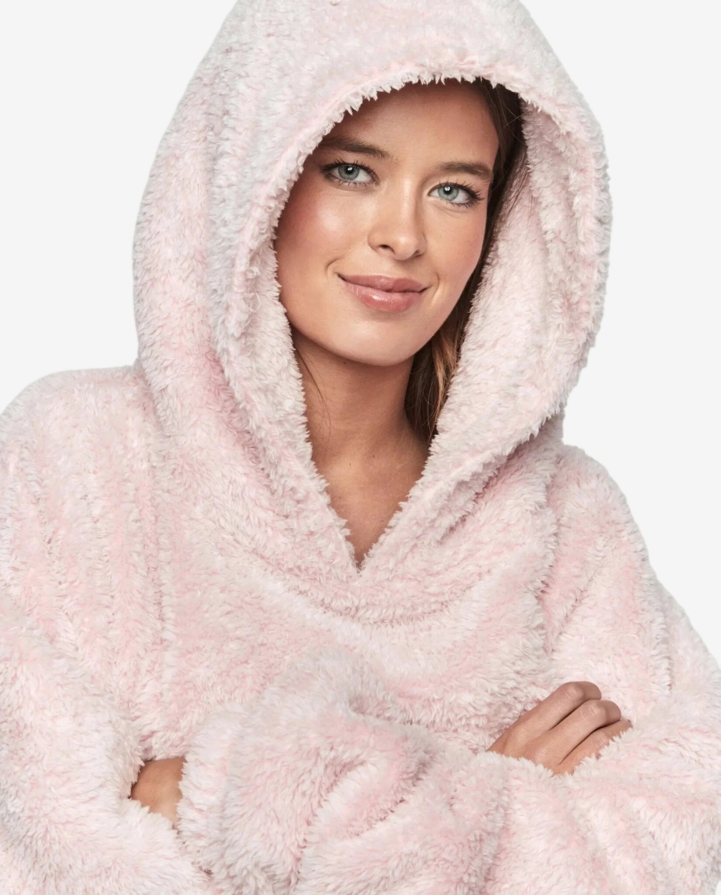 Una donna indossa un abito oversize rosa in tessuto morbido con cappuccio.