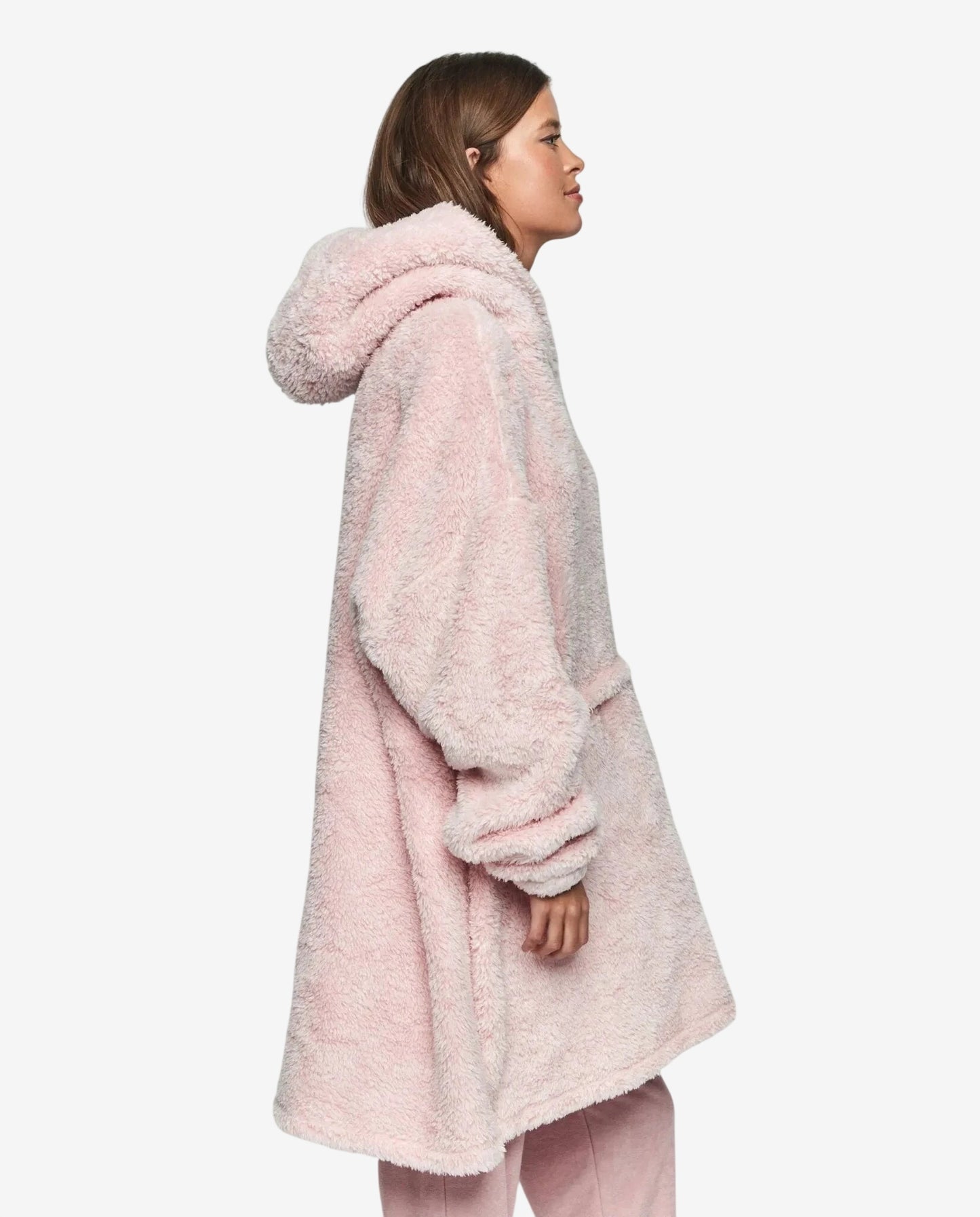 Modella di profilo indossa un abito oversize rosa in morbido tessuto felpato con cappuccio.