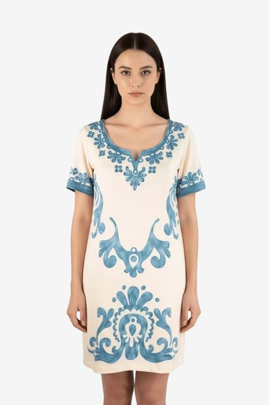Abito corto in lycra color crema con decorazioni floreali blu e strass su scollo e maniche.