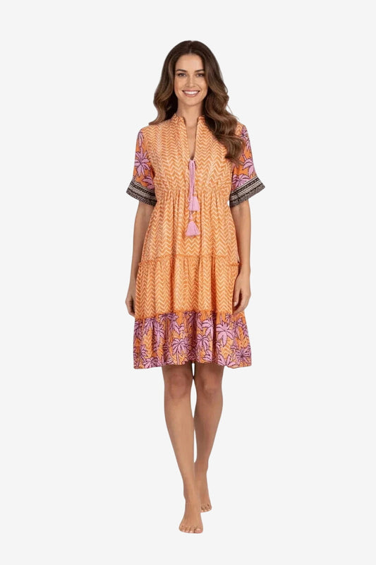 Modella indossa un abito corto arancione con stampa a zig-zag, maniche corte e balza inferiore.