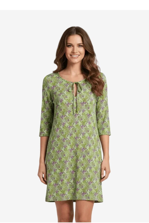 A woman wears a green, short-sleeved dress with a floral pattern and a tie-front neckline.