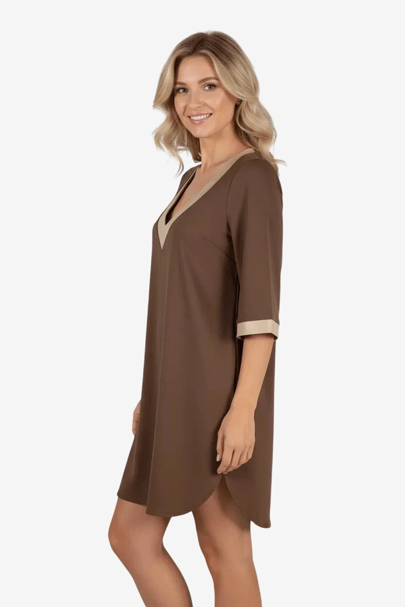 Una modella indossa un abito corto marrone con scollo a V e bordi color crema.