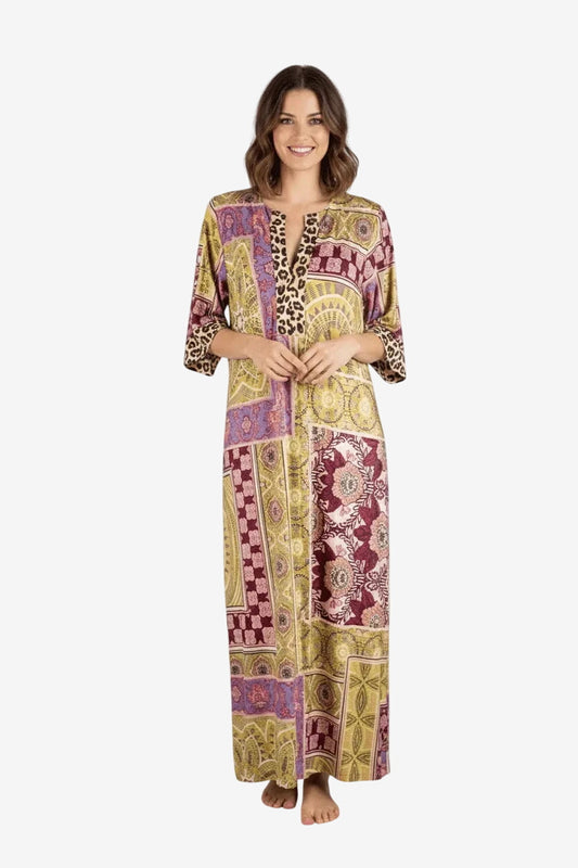 Modella che indossa un abito lungo a maniche a tre quarti con stampa patchwork nei toni dell'oro.