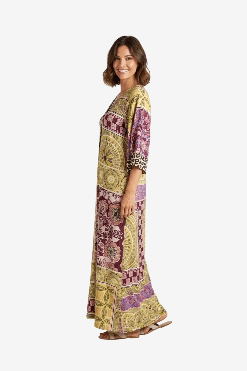 Modella indossa un abito lungo Olivia Gold con stampa geometrica e floreale nei toni dell'oro.