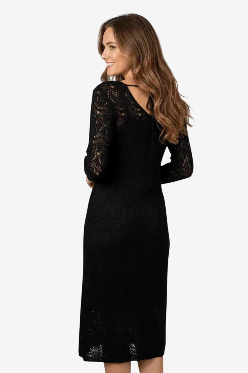 Modella di spalle indossa un abito lungo nero in maglia traforata con scollo posteriore.