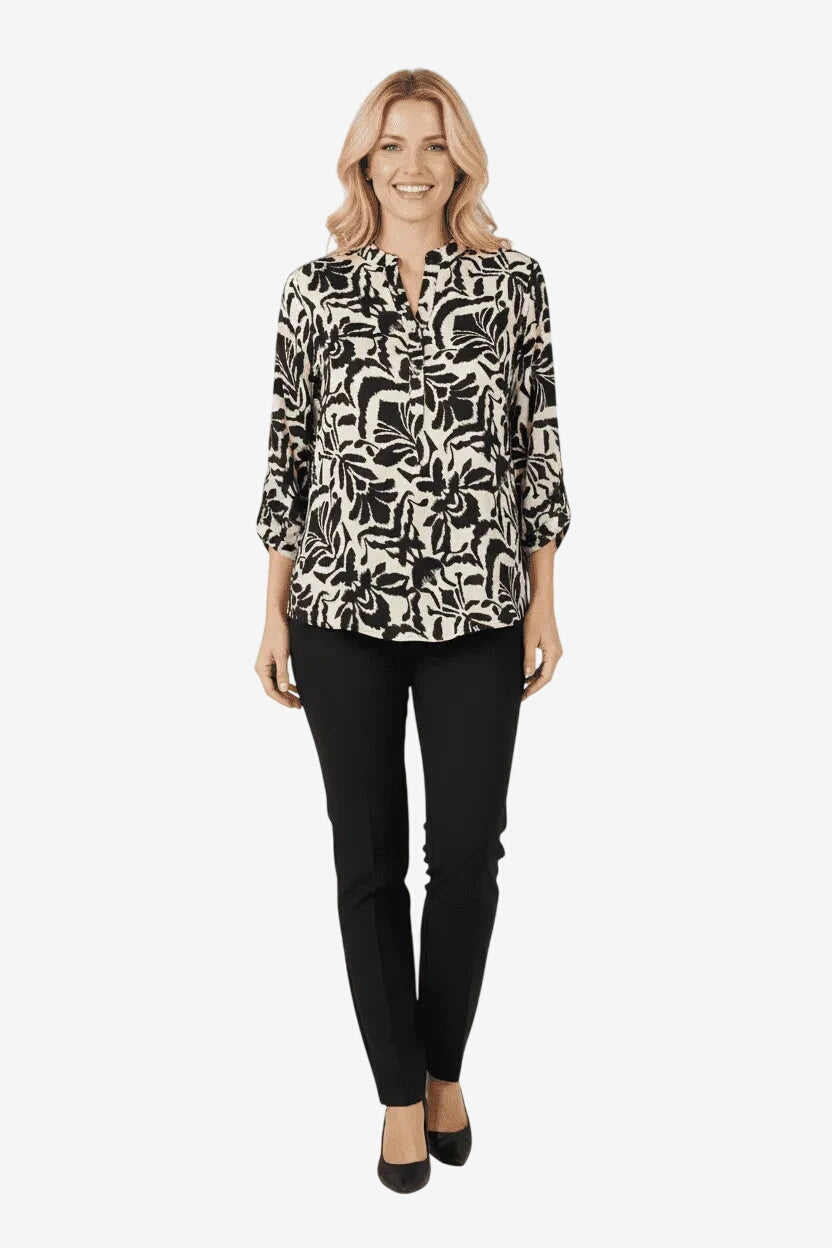 Modella indossa una blusa in viscosa con stampa damascata nera e bianca e pantaloni neri.