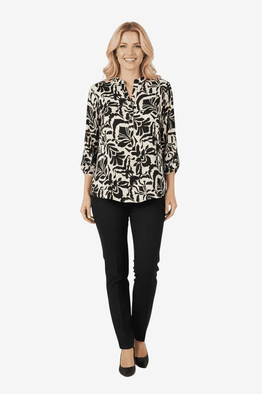 Modella indossa una blusa in viscosa con stampa damascata nera e bianca e pantaloni neri.