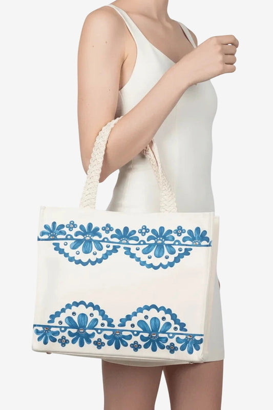 Borsa in canvas bianco con stampa floreale blu, decorazioni in strass e manici in macramè.