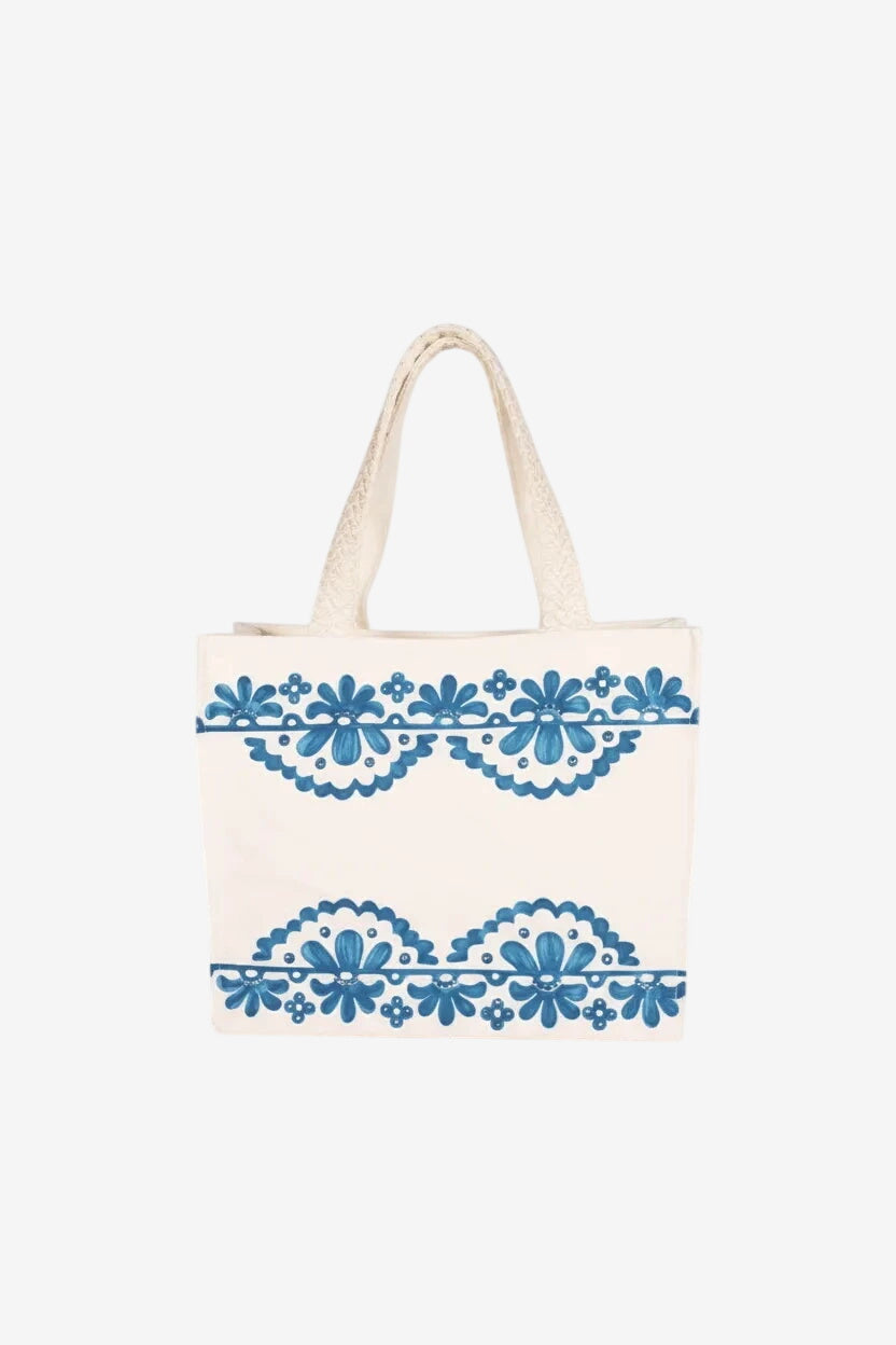 Borsa in canvas color crema con decorazioni floreali blu, strass e manici in macramè.
