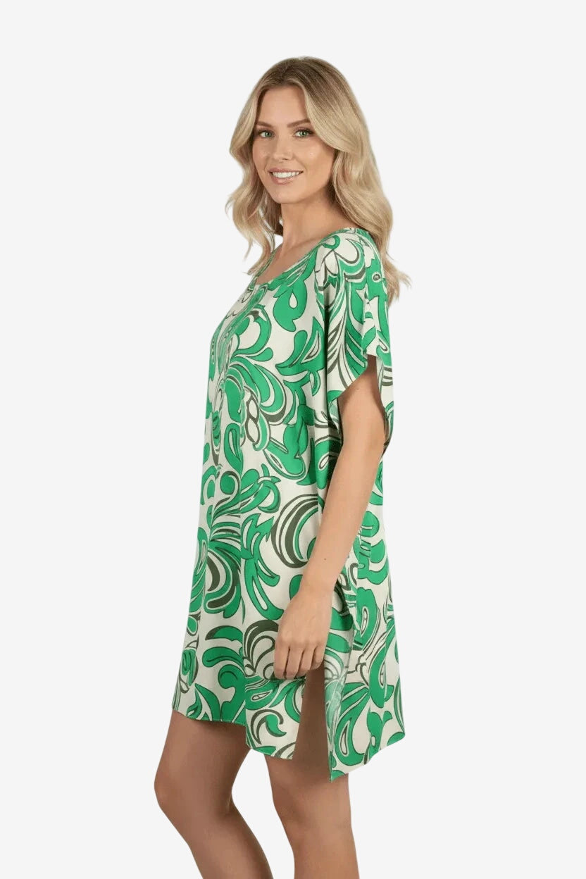 Donna che indossa un caftano corto bianco e verde con stampa astratta e spacchi laterali.