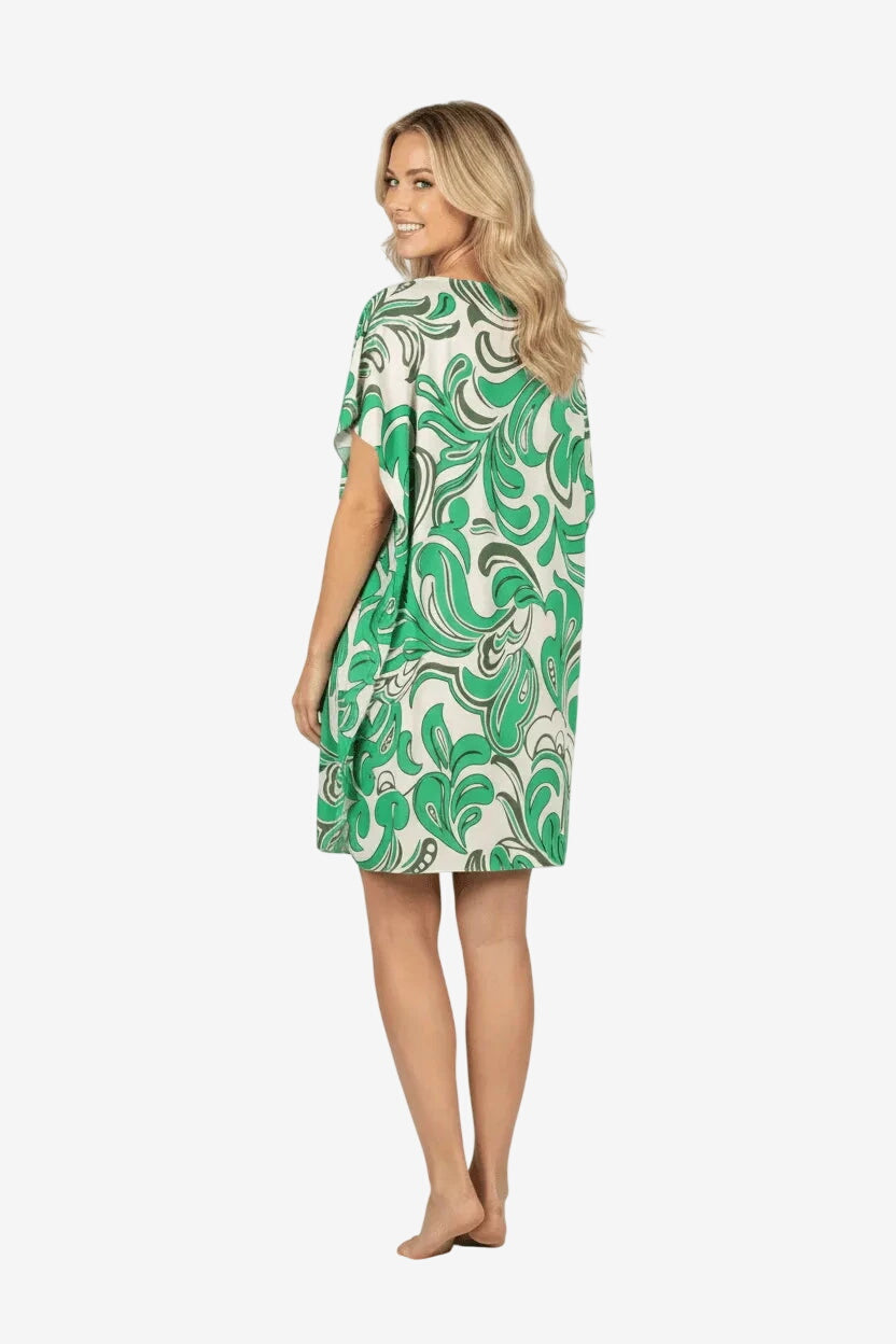 Donna di spalle indossa un caftano corto bianco e verde con fantasia astratta.