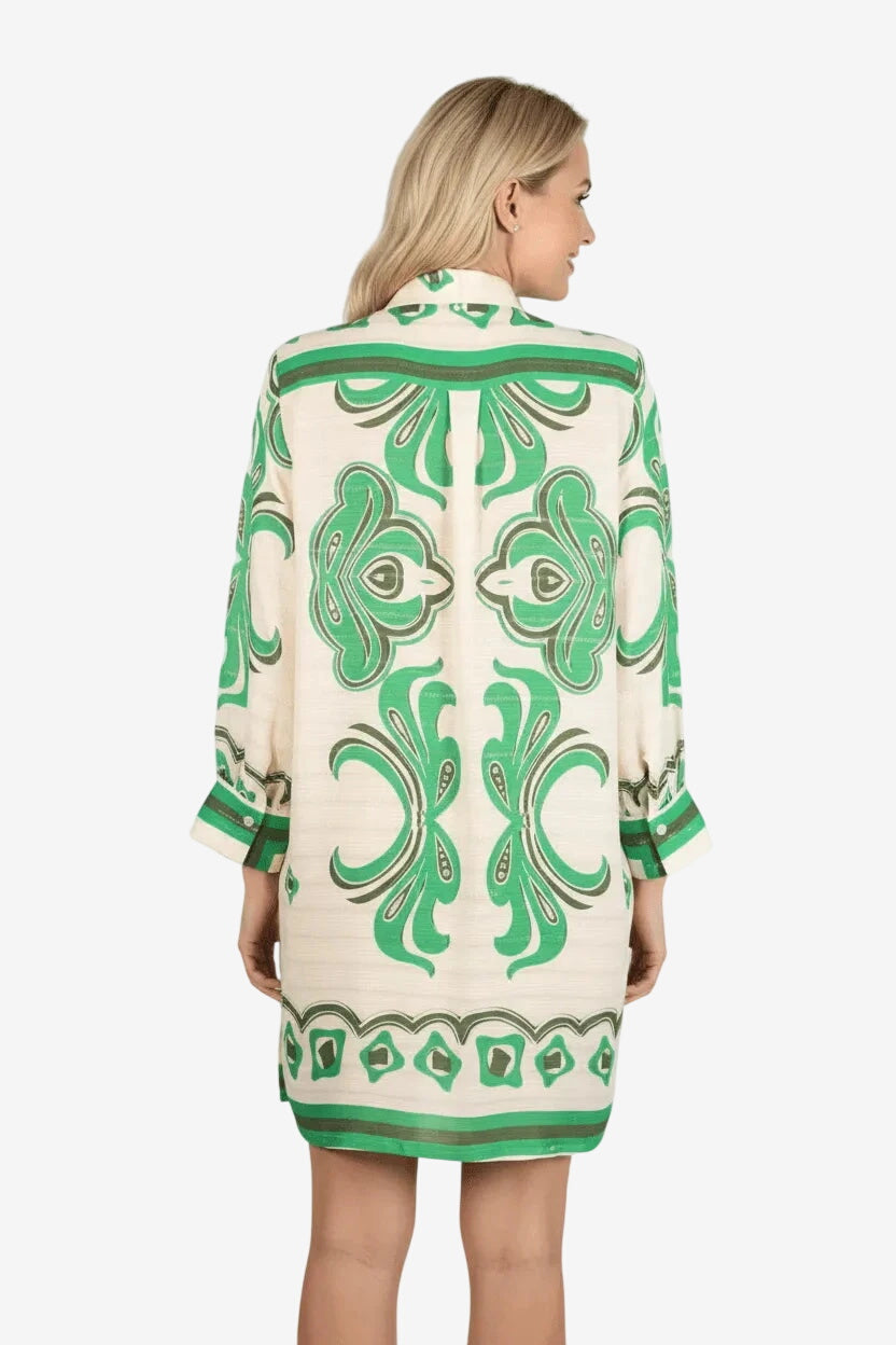 Donna di spalle indossa un camicione in viscosa color crema con una fantasia geometrica verde.