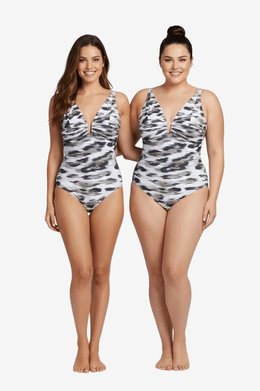 Two women wearing matching one-piece swimsuits with a grey and white abstract animal print.