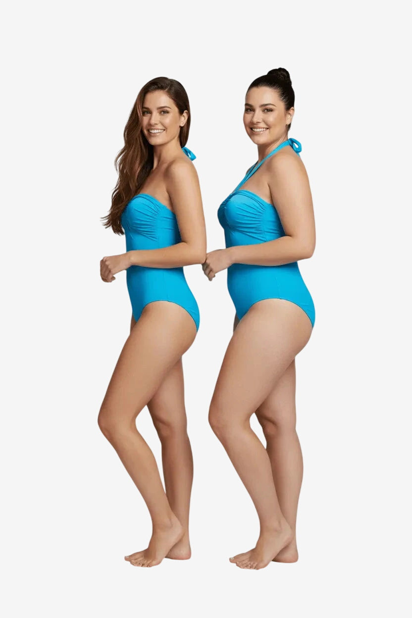 Two women stand side by side wearing identical bright blue strapless one-piece swimsuits.