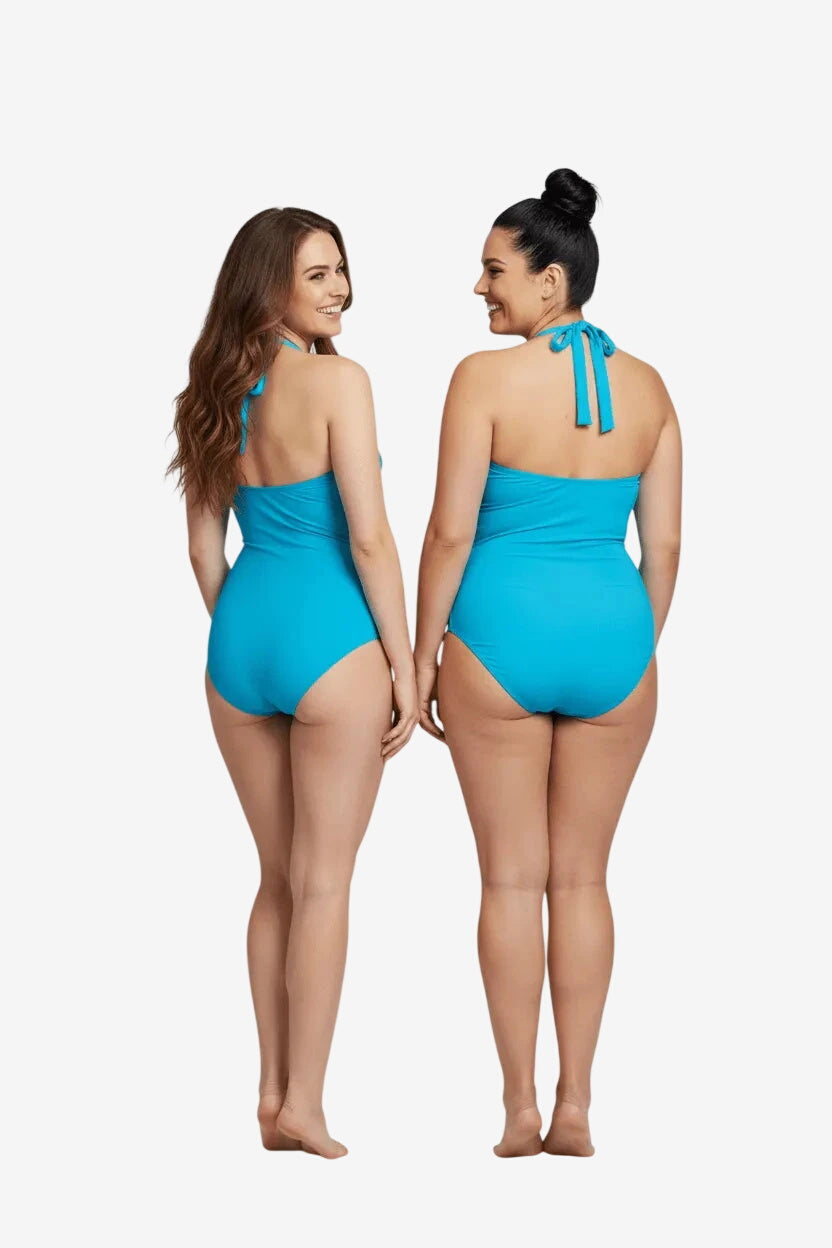 Two women stand back-to-back wearing matching bright blue halter-neck one-piece swimsuits.