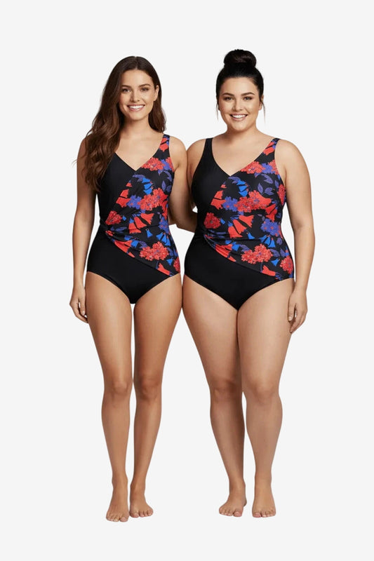 Two women wearing matching black one-piece swimsuits with a red and blue floral side panel.