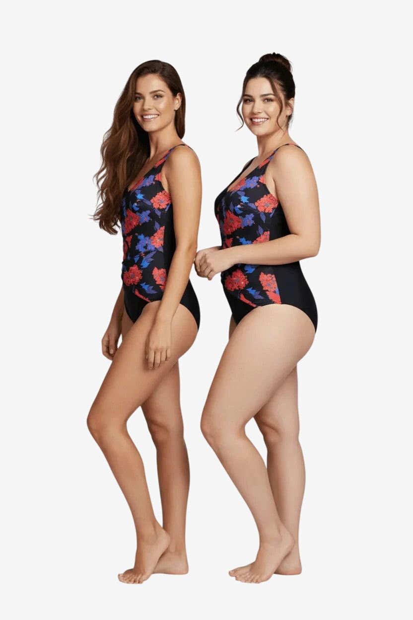 Two women wearing a black one-piece swimsuit with a red and blue floral pattern.
