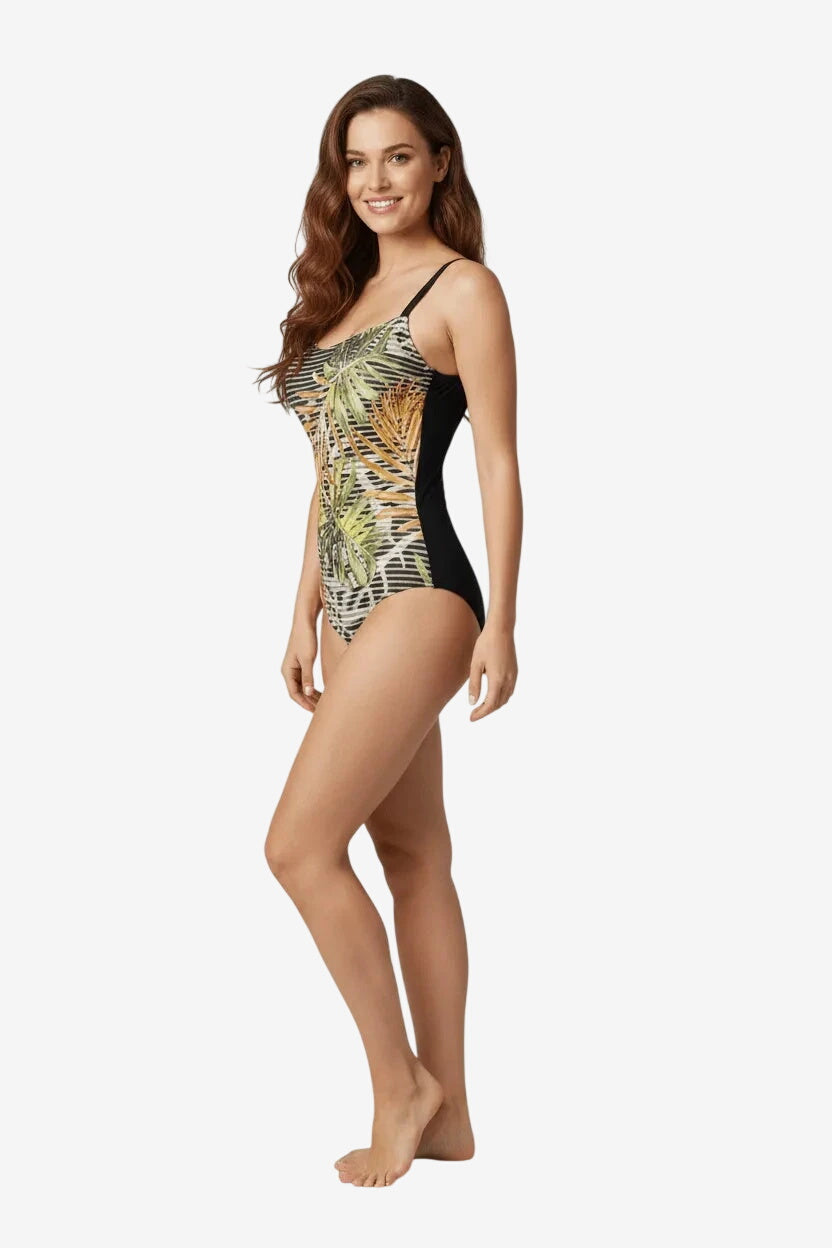 Modella che indossa un costume intero Unimar con stampa tropicale e inserti laterali neri.