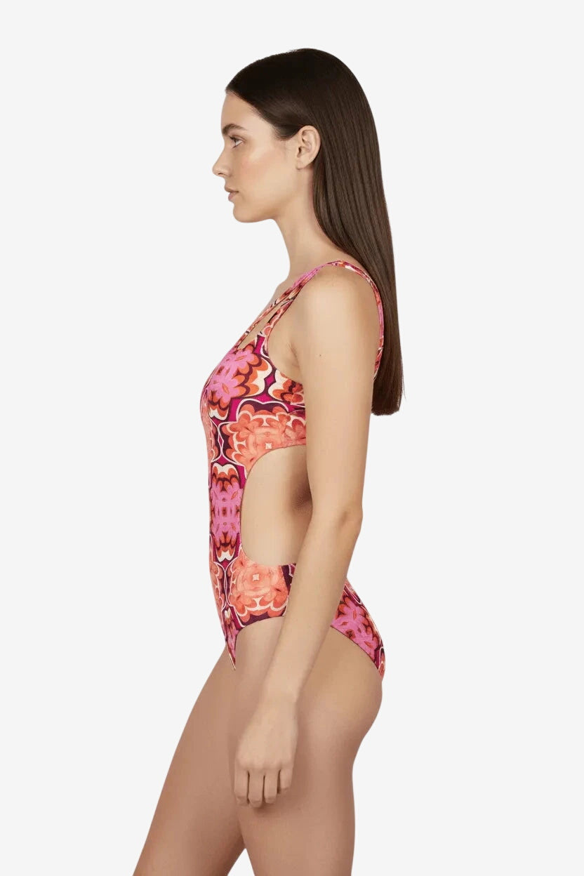 Modella indossa un trikini monospalla con fantasia corallo su sfondo bianco.