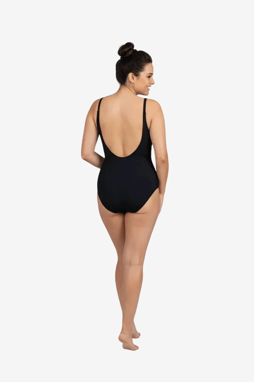 Donna di spalle indossa un costume intero nero dal taglio classico con scollatura sulla schiena.