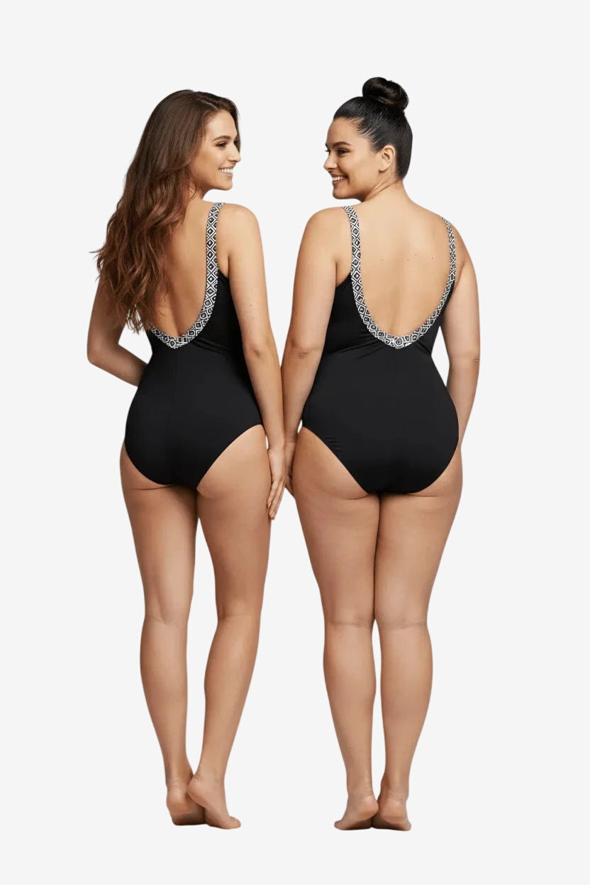 Due modelle indossano un costume intero nero con scollo profondo sulla schiena e dettagli geometrici.