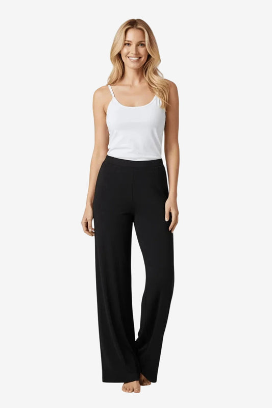 A woman wearing a white tank top and black wide-leg lounge pants.