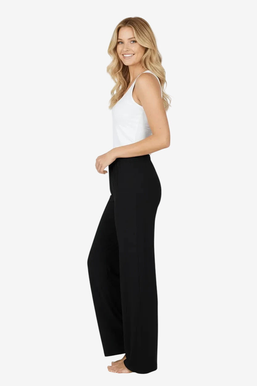 Una modella indossa un pantalone nero a gamba larga con un top bianco senza maniche.