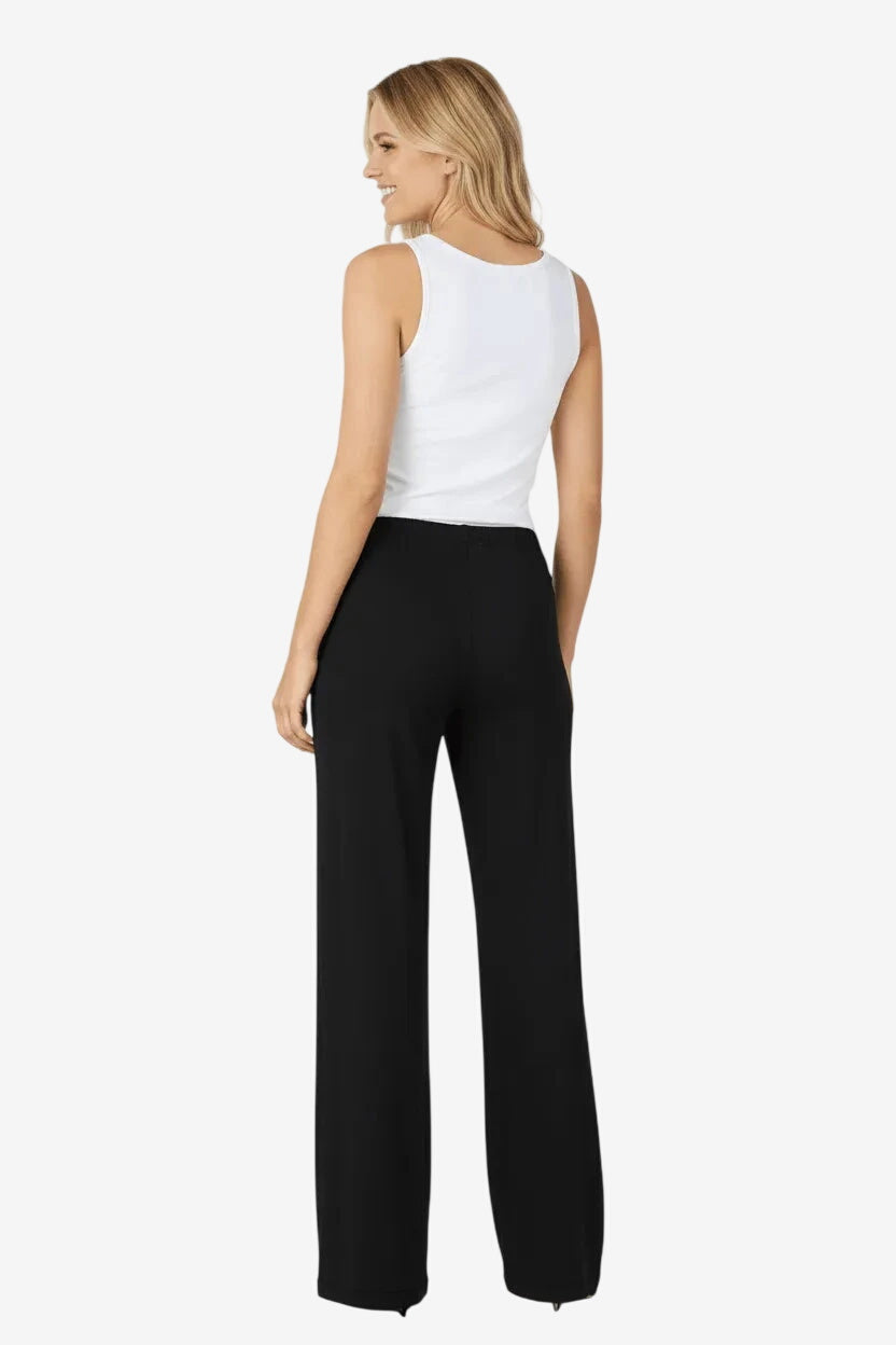 A woman seen from behind wearing a white tank top and black wide-leg trousers.