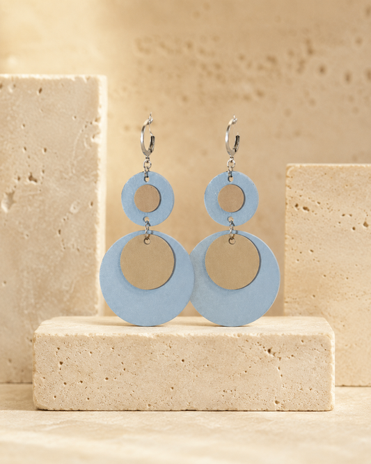 Orecchini pendenti composti da due cerchi in pelle color azzurro e beige su ganci in acciaio.