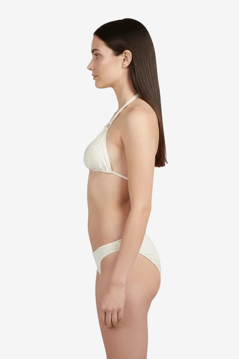 Modella di profilo indossa un bikini a triangolo color panna crema.