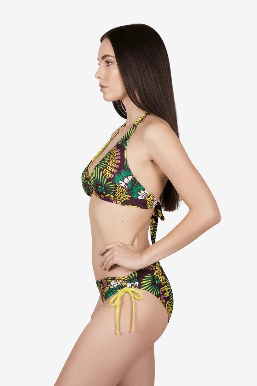 Modella di profilo indossa un bikini triangolare con stampa tropicale gialla, verde e viola.