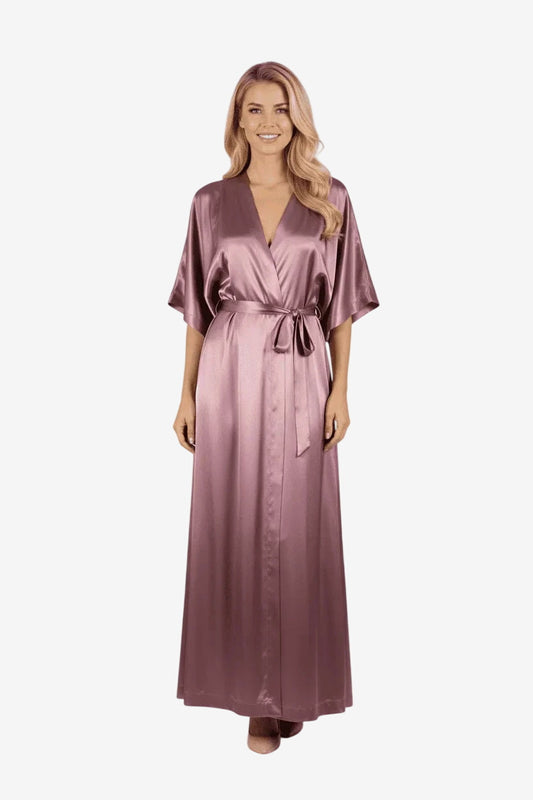 Una donna indossa un vestito lungo color malva in tessuto satinato con maniche ampie e cintura.